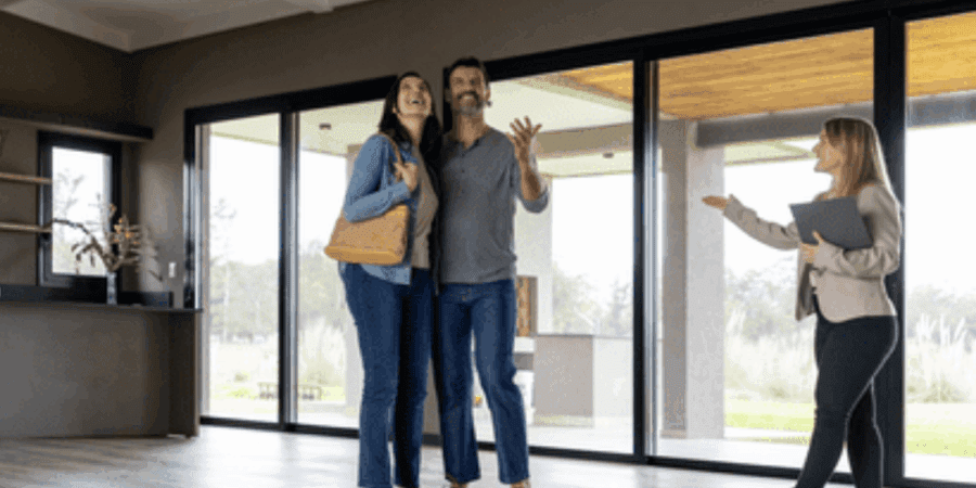 People touring a modern, empty living room.