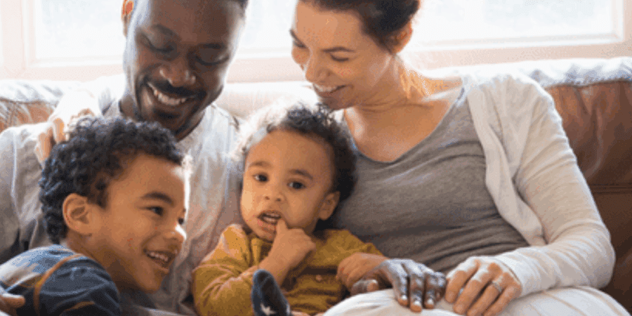Smiling family sitting on a couch.